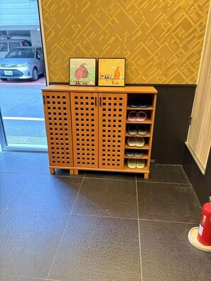 Un zapatero de madera con varias repisas, un extintor y un vehículo afuera.