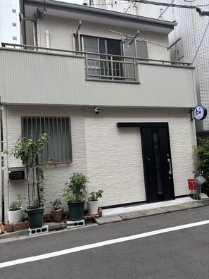 A two-story building with a black door and a small balcony.