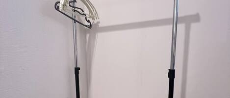 A corner room with a metal rack against the wall, a white floor, and a visible electrical outlet.
