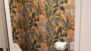 Une salle de bain équipée de toilettes, d’un distributeur d’essuie-tout et d’un papier peint à motifs.