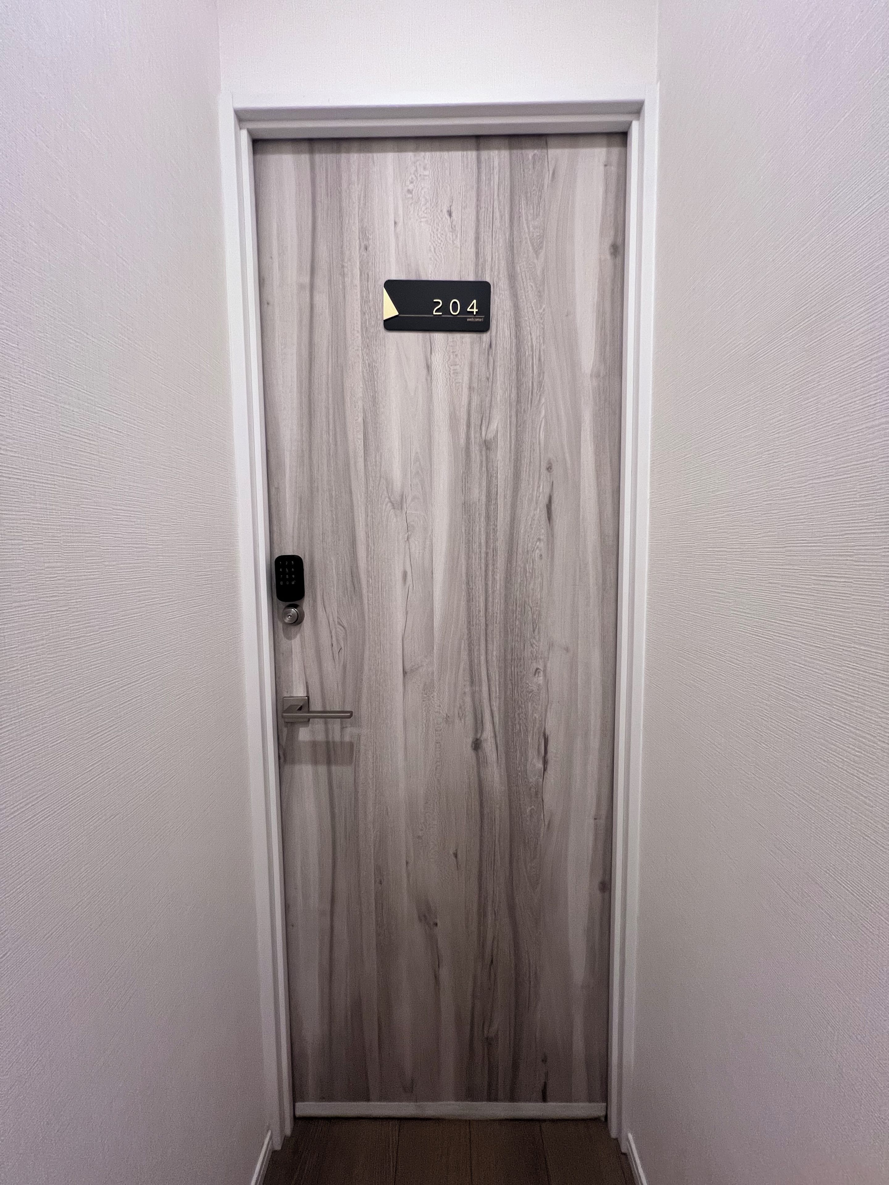 A door with a number plate indicating room 204, a door handle, and a door frame.