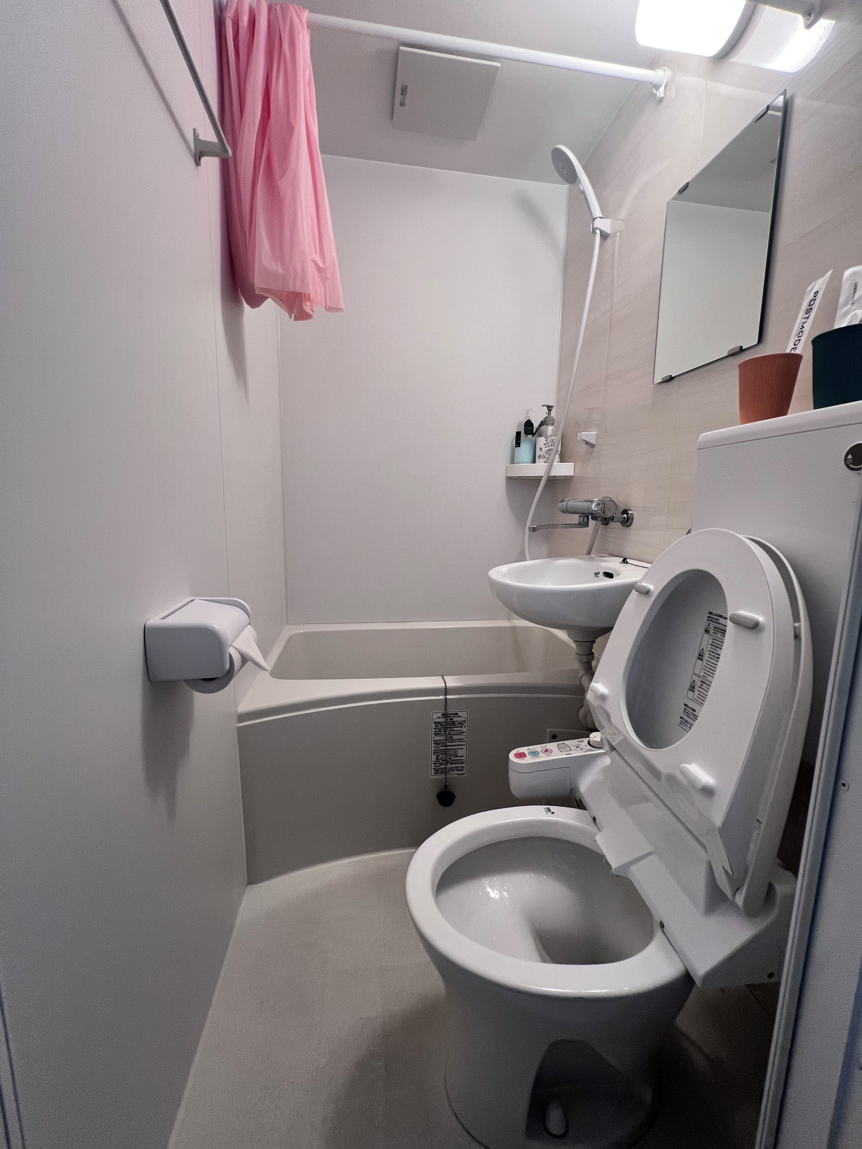 A compact bathroom with a toilet, sink, and shower.