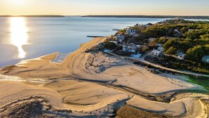 A coastal area with sandy beaches, a clear sky, and a row of houses with a view of the water. - Bay Views, Steps to Beach, Minutes to P-Town (Wellfleet)