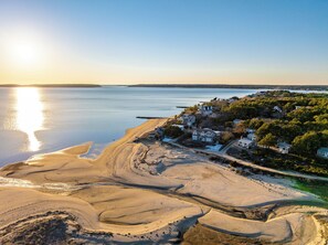 A coastal area with sandy beaches, a clear sky, and a row of houses with a view of the water. - Bay Views, Steps to Beach, Minutes to P-Town (Wellfleet)