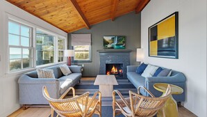 A cozy living room with a fireplace, two sofas, wicker chairs, and a coffee table. - Bay Views, Steps to Beach, Minutes to P-Town (Wellfleet)