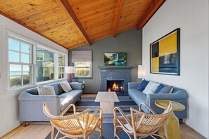 A cozy living room with a fireplace, two sofas, wicker chairs, and a coffee table. - Bay Views, Steps to Beach, Minutes to P-Town (Wellfleet)
