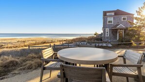 A coastal house with a round table and wooden chairs, overlooking the beach. - Bay Views, Steps to Beach, Minutes to P-Town (Wellfleet)