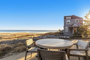 A coastal house with a round table and wooden chairs, overlooking the beach. - Bay Views, Steps to Beach, Minutes to P-Town (Wellfleet)