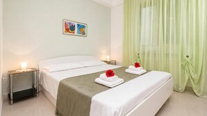 A hotel room with two beds, a nightstand with a lamp, a painting on the wall, and green curtains. - Marisa Olive Grove - App Terra, Labin, Croatia (Labin)