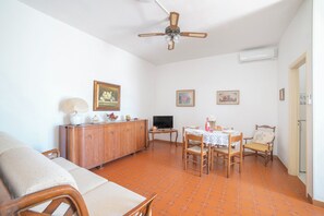 A living room with a sofa, dining table, chairs, a TV, and a ceiling fan. - Leuca Relax&Sea n.8a, Castrignano del Capo, Italy (Castrignano del Capo)