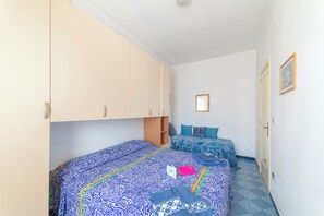 A bedroom with two beds, a wardrobe, and a small shelf. - Leuca Relax&Sea n.8a, Castrignano del Capo, Italy (Castrignano del Capo)