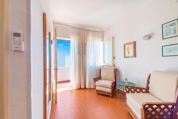 A hotel room with a balcony, a chair, a small table, and a sofa. - Leuca Relax&Sea n.8a, Castrignano del Capo, Italy (Castrignano del Capo)