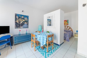 A room with a bed, a desk with a computer, a chair, a table with a tablecloth, and a wall with artwork. - Leuca Relax&Sea n.2a, Castrignano del Capo, Italy (Castrignano del Capo)