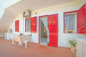 A room with a table and chairs, a red door, and a window with a bowl of fruit. - Leuca Relax&Sea n.2a, Castrignano del Capo, Italy (Castrignano del Capo)
