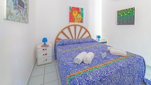 Ein Schlafzimmer mit einem hölzernen Bett, einem Nachttisch, zwei Wandbildern.