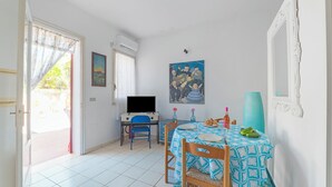 Ein Zimmer mit Esstisch, Stühlen, einem Fernseher und einem Gemälde an der Wand.