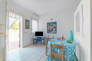 A room with a dining table, chairs, a television, and a painting on the wall. - Leuca Relax&Sea n.2a, Castrignano del Capo, Italy (Castrignano del Capo)
