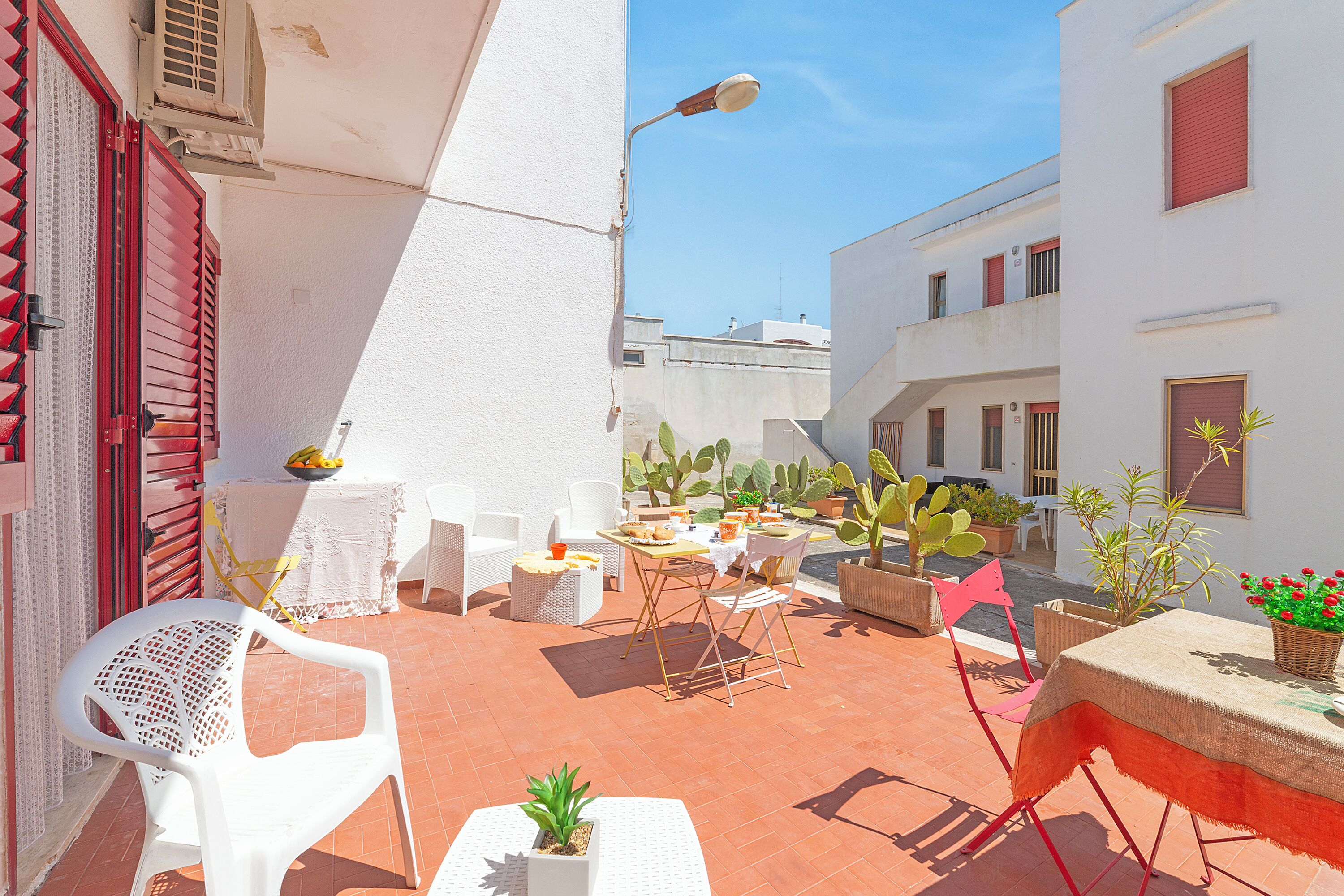 A courtyard with outdoor seating, potted plants, and a street lamp.