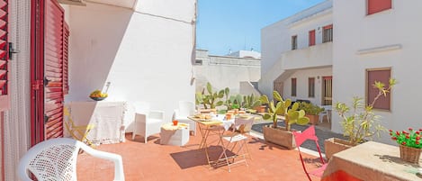 A courtyard with outdoor seating, potted plants, and a street lamp.
