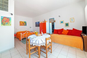 Ein Schlafzimmer mit einem Bett, einem Tisch mit Stühlen, einem Kleiderschrank und einem Spiegel.