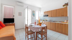 A room with a bed, a dining table with chairs, a kitchen area, and an air conditioning unit. - Leuca Relax & Sea n.1b, Castrignano del Capo, Italy (Castrignano del Capo)