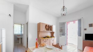 Un coin repas avec une table dressée pour deux personnes, un buffet en bois et un téléviseur placé dans un coin.