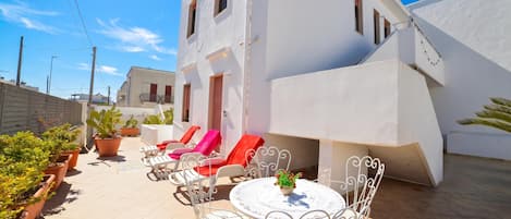 A white building with a patio area featuring outdoor seating and potted plants.