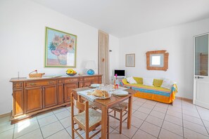 A room with a dining table, chairs, a sofa, a cabinet, and a painting on the wall. - Leuca Relax & Sea n.4bbis, Castrignano del Capo, Italy (Castrignano del Capo)