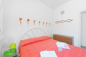 A bedroom with a white bed, a green chair, a wooden dresser, and a wall with flower decorations. - Leuca Relax & Sea n.4bbis, Castrignano del Capo, Italy (Castrignano del Capo)