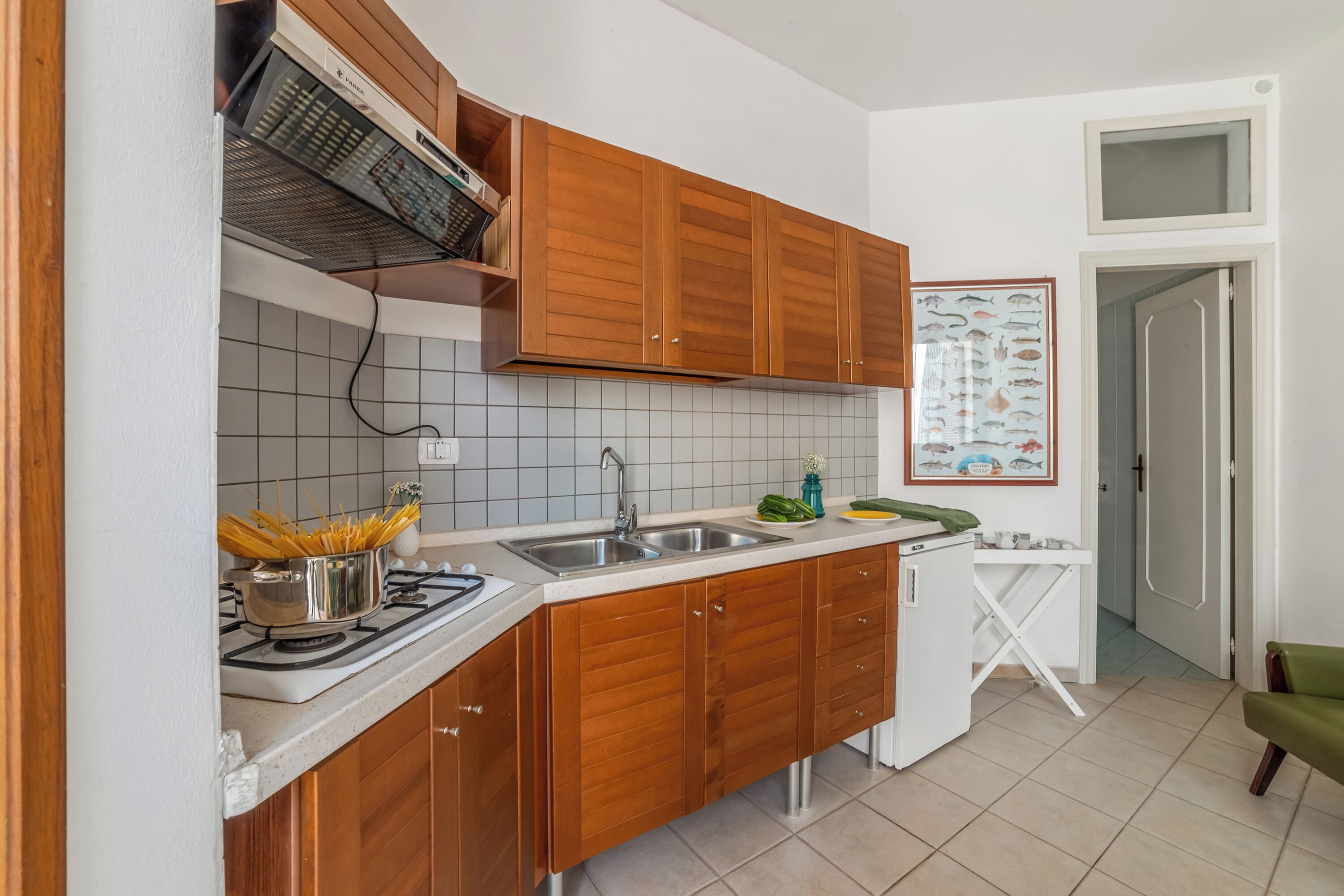 Una cucina con mobili in legno, un lavello, un fornello e un piccolo tavolo bianco.