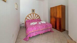 Ein Schlafzimmer mit einem Bett, einem Holzschrank, einem kleinen Tisch und einem Stuhl.