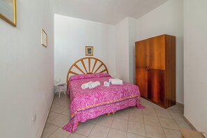 Ein Schlafzimmer mit einem Bett, einem Holzschrank, einem kleinen Tisch und einem Stuhl.