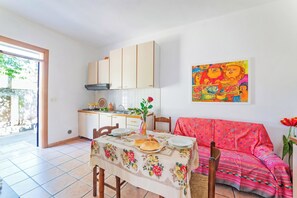 A dining area with a table set for two, a sofa, and a kitchen in the background. - Leuca Relax&Sea n.3bbis, Castrignano del Capo, Italy (Castrignano del Capo)