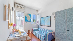 Ein Zimmer mit Esstisch, Stühlen, einem gestreiften Sofa, einer Karte an der Wand und einer Klimaanlage.