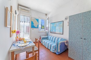 A room with a dining table, chairs, a striped sofa, a map on the wall, and an air conditioning unit. - Leuca Relax&Sea n.3b, Castrignano del Capo, Italy (Castrignano del Capo)