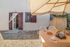 A dining area with a table set for two, a small window with shutters, and a covered outdoor seating area. - Leuca Relax&Sea n.2bbis, Castrignano del Capo, Italy (Castrignano del Capo)