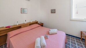 Et hotelværelse med en seng, et trænatbord, et vindue og en vægmonteret aircondition.