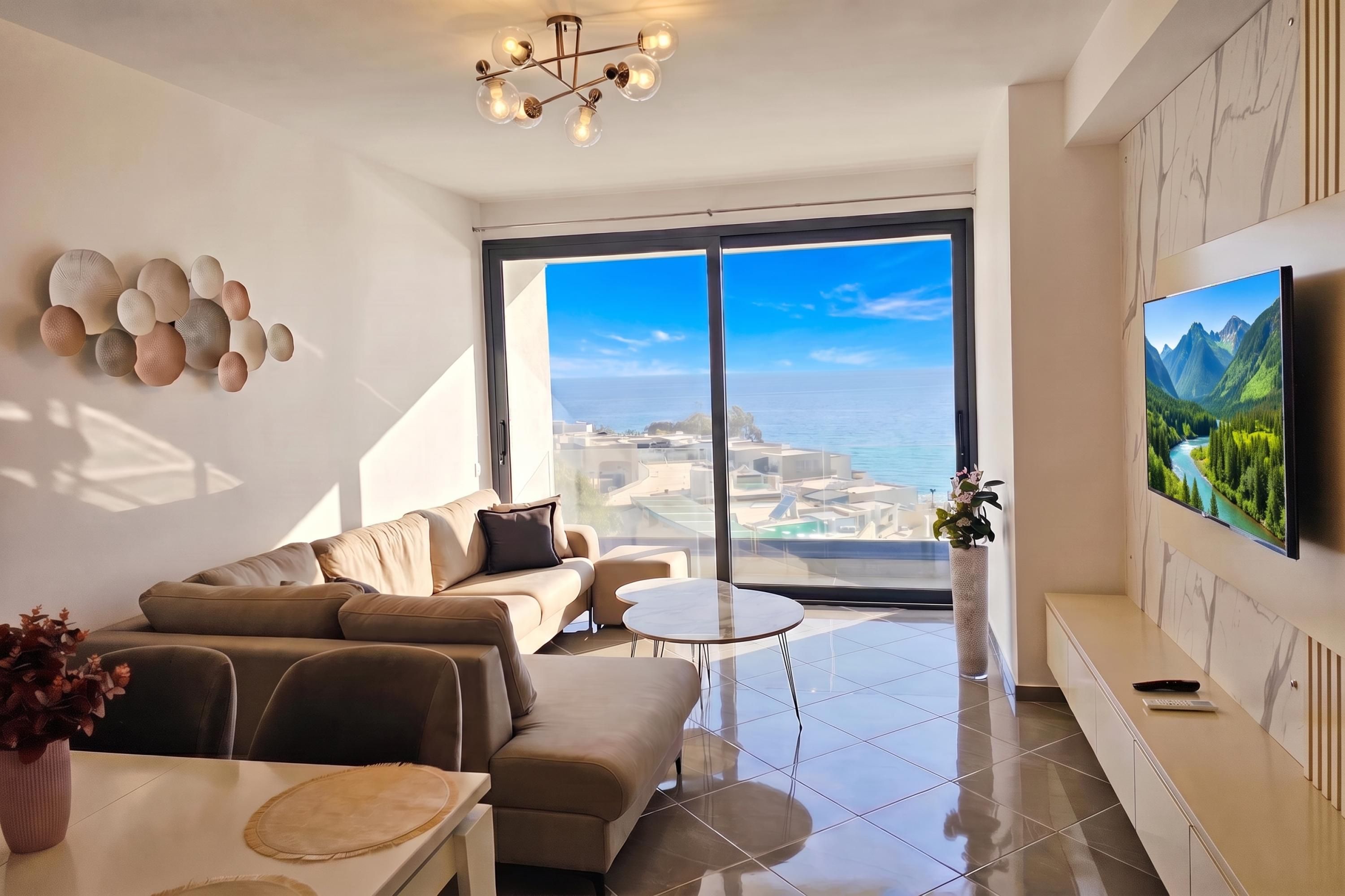 A modern living room with a large window, a sofa, a coffee table, and a flat-screen TV.