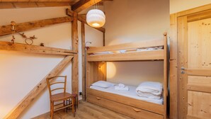 A wooden bunk bed room with a chair, a hanging light fixture, and a wooden door. - Chalet Les Airelles Mont-Blanc View, Chamonix, France (Chamonix)