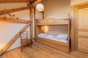 A wooden bunk bed room with a chair, a hanging light fixture, and a wooden door. - Chalet Les Airelles Mont-Blanc View, Chamonix, France (Chamonix)