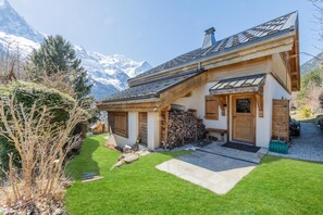 Eine zweistöckige Chalet mit geneigtem Dach, Holzfassade und Steinuntergrund.