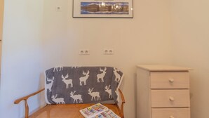 A room with a wooden chair, a small table with a magazine, a framed picture on the wall, and a white dresser. - Chalet Les Airelles Mont-Blanc View, Chamonix, France (Chamonix)