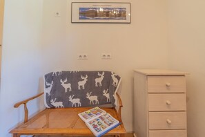 A room with a wooden chair, a small table with a magazine, a framed picture on the wall, and a white dresser. - Chalet Les Airelles Mont-Blanc View, Chamonix, France (Chamonix)