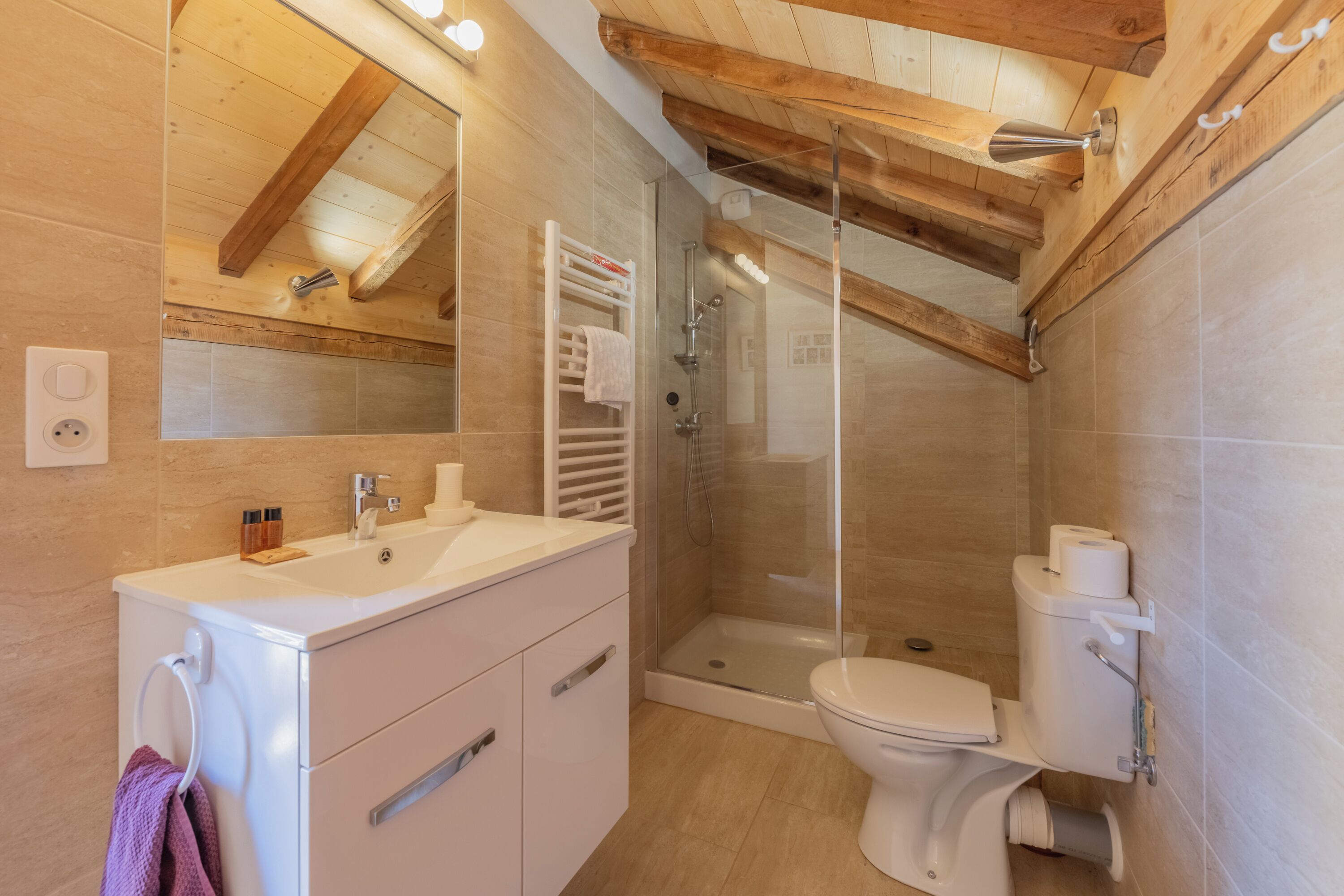 Une salle de bain moderne avec un plafond en bois, une douche en verre, un lavabo blanc et des toilettes.