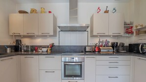 A modern kitchen with white cabinets, a built-in oven, and various kitchen appliances. - Chalet Les Airelles Mont-Blanc View, Chamonix, France (Chamonix)