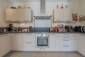 A modern kitchen with white cabinets, a built-in oven, and various kitchen appliances. - Chalet Les Airelles Mont-Blanc View, Chamonix, France (Chamonix)