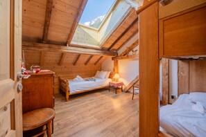A wooden cabin with a loft bedroom, a small seating area, and a window with a mountain view.