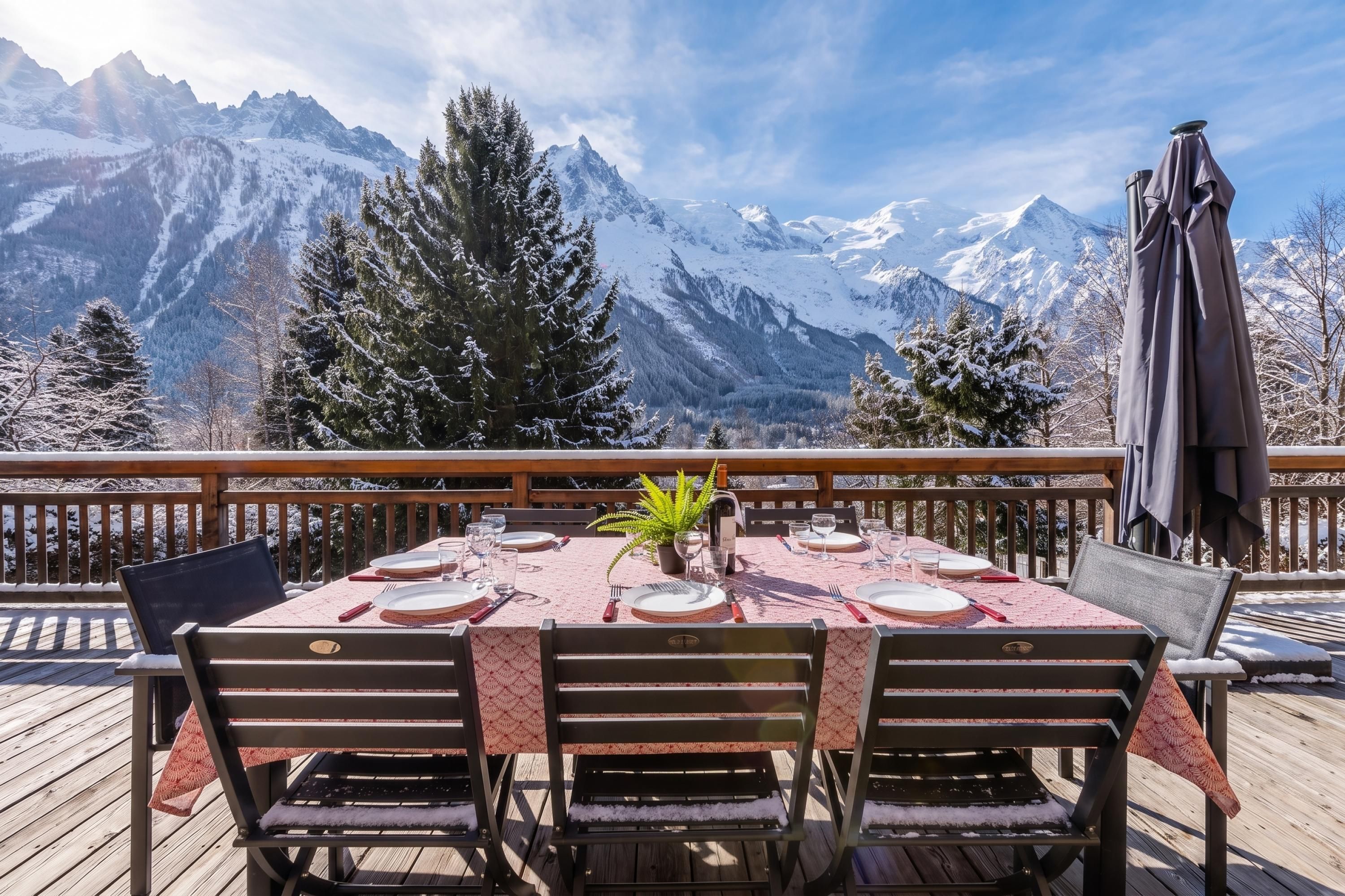 Ein Esstisch im Freien mit Blick auf die Berge, einer Holzterrasse und Stühlen.