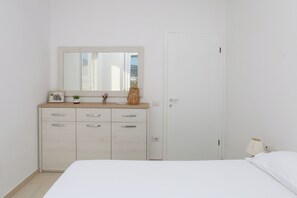 A bedroom with a bed, a dresser with drawers, a mirror, and a door. - Richard Sea View Apartment, Vlore, Albania (Vlore)