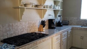 Une cuisine équipée d’une cuisinière à gaz, d’une machine à café et d’un grille-pain posés sur le plan de travail.